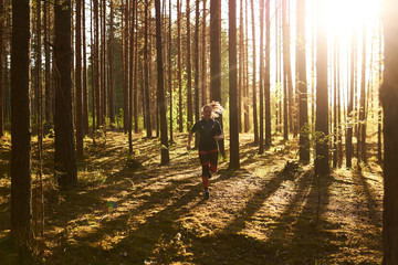 young woman jogging in a pine forest