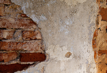 Old red brick wall with stucco remains. The texture of the brickwork.
