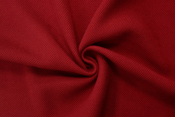 Red background of fabric from a piece of crumpled clothes. Top view. crumpled polyester. The texture of the fabric, useful as a backdrop.