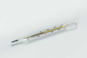 the mercury thermometer is lying on a white table. the thermometer shows a temperature of 36.6 degrees Celsius