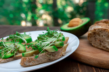 sandwiches with avocado and microgreen cressalate close-up on a wooden background. Healthy diet. Feed option. vegetarianism. horizontal photo.