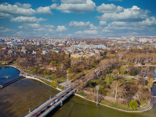 Top view on Secheni baths, Budapest city park. People are resting on the green grass. Lakes and bridge in the park. Spring. Trees without leaves and with green leaves.
