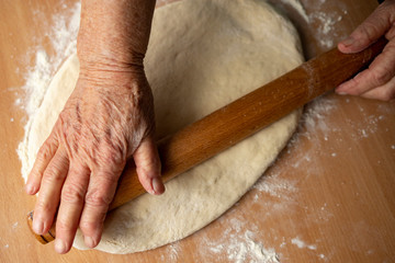 Grandmother's hands close-up prepare homemade dough.