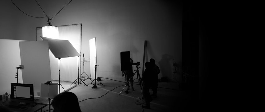 Shooting studio for photographer and creative art director with production crew team setting up lighting flash and LED headlight on tripod and professional equipment for portrait model photo shoot