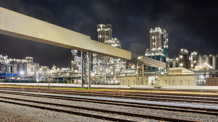 Night scene with illuminated petrochemical production plant and train rails on the foreground, Antwerp, Belgium.