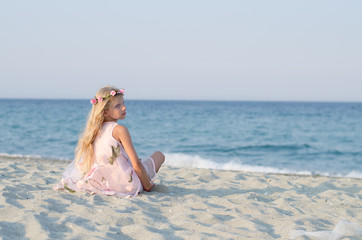 Fototapeta na wymiar little child sitting back view alone by the sea