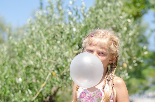 little child with huge bubble from chewing gum