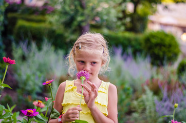 lovely innocent blond girl smelling to flowers