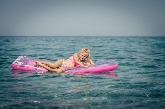 cute girl lying on inflatable pink airbed