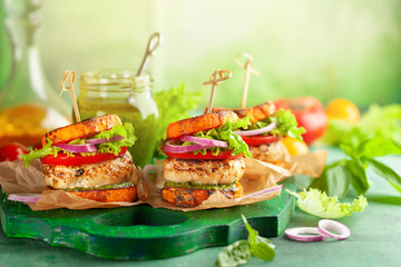 Delicious roasted pumpkin turkey burger with tomatoes and pesto on green wooden board.