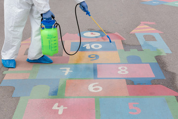 Man wearing protective suit disinfecting the playground  with spray chemicals to preventing the spread of coronavirus, pandemic in quarantine city.