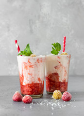 Layered strawberry and raspberry smoothie or milkshake in glasses decorated with mint, raspberry...