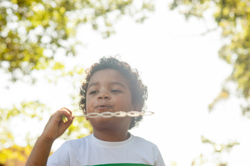 Happy african boy playing with soap bubbles in nature