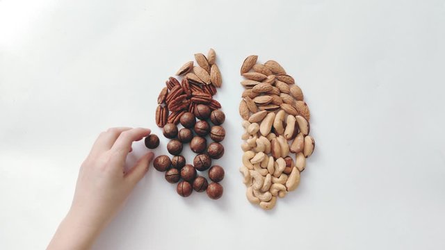 Human hand puts an assorted nut on the table in the form of a human brain.