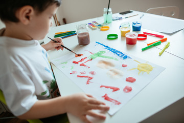 Left handed preschooler boy painting picture.