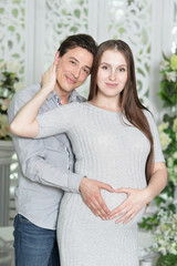 Happy pregnant woman with husband posing at home