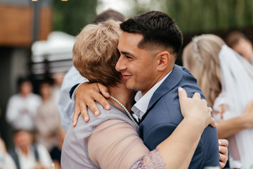 Happy groom emracing his mother during the wedding ceremony