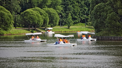Moscow / Russia &ndash; 07 16 2019: pedal boats tourists Catamarans in Tsaritsyno Upper Pond near Round Island on green forest background in Tsaritsino Park Museum on summer day