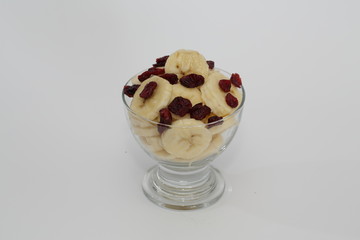 Deser z krojonych bananów i żurawiny w salaterce.