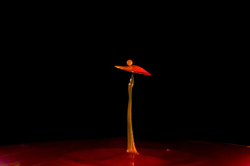 Orange water droplet bounching on water surface with a big splash