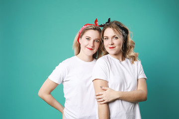 Two blonde young caucasian women twins hugging each other  in white t-shirt isolated on green background