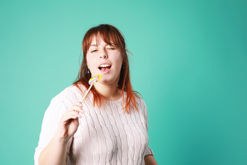  Funny teenager girl with oversize holding colorful lollipop isolated on green background