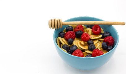 tiny Pancake cereal, mini pancakes in a blue bowl with honey and with special honey spoon on white background. Space for text. Trendy quarantine breakfast