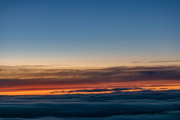 Fototapeta na wymiar Sunset sky with colorful clouds seen through an aircraft window