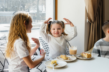 Two cute little girls are sitting in a cafe and playing on a Sunny day. Recreation and lifestyle.