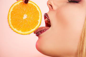 Closeup mouth, tongue and lips of girl in sugar with orange. Food, fashion concept © Alexander