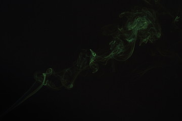 Zielony dym z kadzidła na czarnym tle.