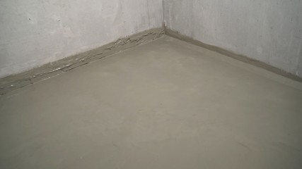 Waterproofing mortar on a concrete floor. A worker applies waterproofing to a concrete floor with a...