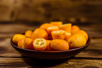 Plate with kumquat fruits on wooden table
