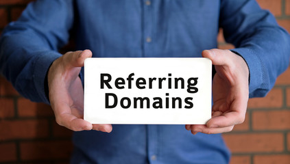 Referring domains - seo concept check the rank of the site in the hands of a young man in a blue shirt