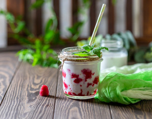 Raspberry smoothie, milkshake in a glass jar on a dark wooden background. Yogurt cocktail. Natural summer detox drink