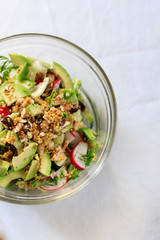salad in a transparent bowl of avocado, walnuts, green salad, radish French mustard on a table with...