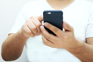 A person is holding a phone and tapping the screen on a white background with copy space. Concept of lifestyle business and Internet technologies in the office