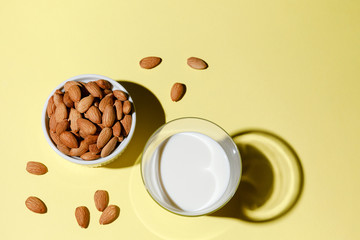 Alternative dairy - almond milk in a glass on yellow background.