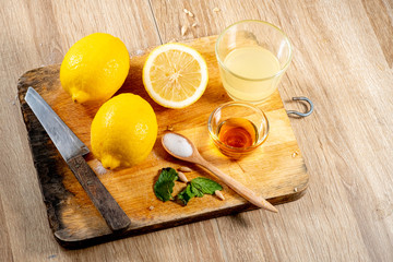 Freshly squeezed lemon juice and mint leave in clear glass cup on wooden chopping board and clean...