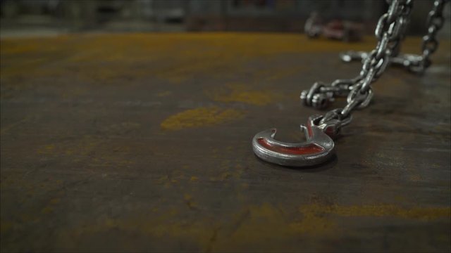 Low angle view of manual worker operating crane lifting sheet metal in industry. Crane in the factory lifts metal sheets