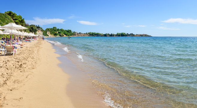 Pefkos beach with holiday-makers, sun beds and umbrellas in village of Pefkos - PANORAMA (Rhodes, Greece)