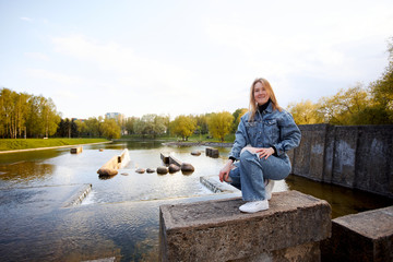 Beautiful portrait of a 90s redhead scandinavian teenager girl in jeans in a park near a lake