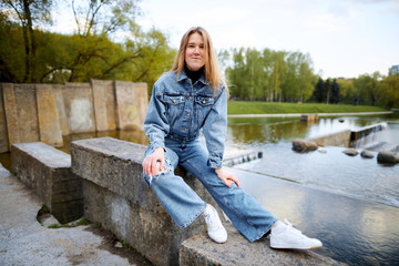 Beautiful portrait of a 90s redhead scandinavian teenager girl in jeans in a park near a lake