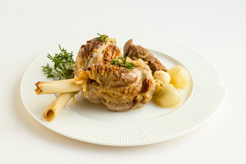Well cooked three pieces of lamb shank in the stylish,white porcelain plate with fresh thyme,union and garlic.Conceptual image for feasts.