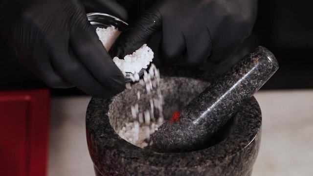 Chef pours spices into a mortar
