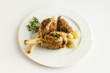 Well cooked three pieces of lamb shank in the stylish,white porcelain plate with fresh thyme,union and garlic.Conceptual image for feasts.