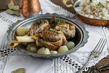 Lamb shank,rice and buttermilk drink,served on wooden table with handmade lace tablecloth and old vintage copper dishes.Traditional Islamic Feast or any holiday concept.