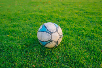 Plakat A white, blue football ball placed on a green lawn.soccer ball on a green grass.