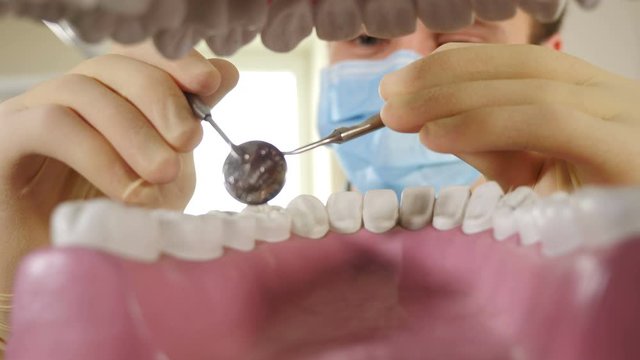 Personal Or Patient Point Of View, POV. Dentist Looking Inside Mouth Model And Holding Dental Tools For Examination. In Dental Clinic. Close-up View On Male Stomatologist Through Teeth. 4 K Video