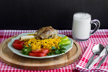 Traditional Arabic rice with tomato,pepper,parsley and lamb shank in plate,on wooden tray with cold drink,cutlery set and napkin.